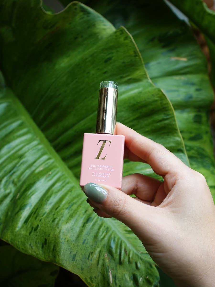 POSH's own photo: a hand holding a Tuesday in Love gel polish bottle (the TIL mark untouched) against green leaves. No words on it.